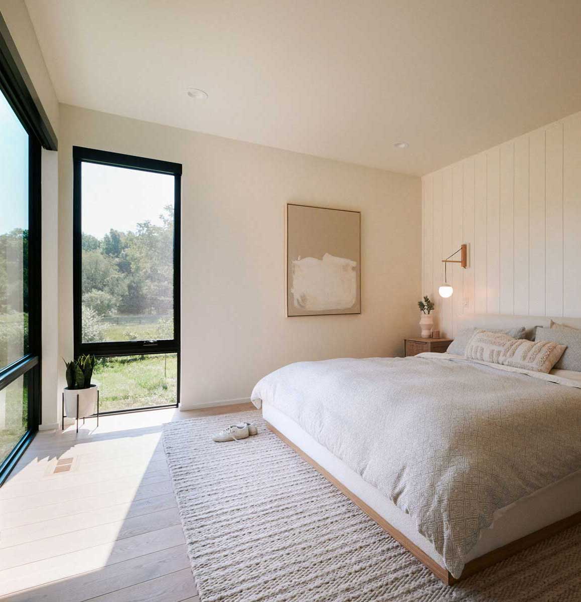 A minimalist bedroom with lots of light cream colors features lots of natural light from Marvin Essential Direct Glaze and Casement windows.