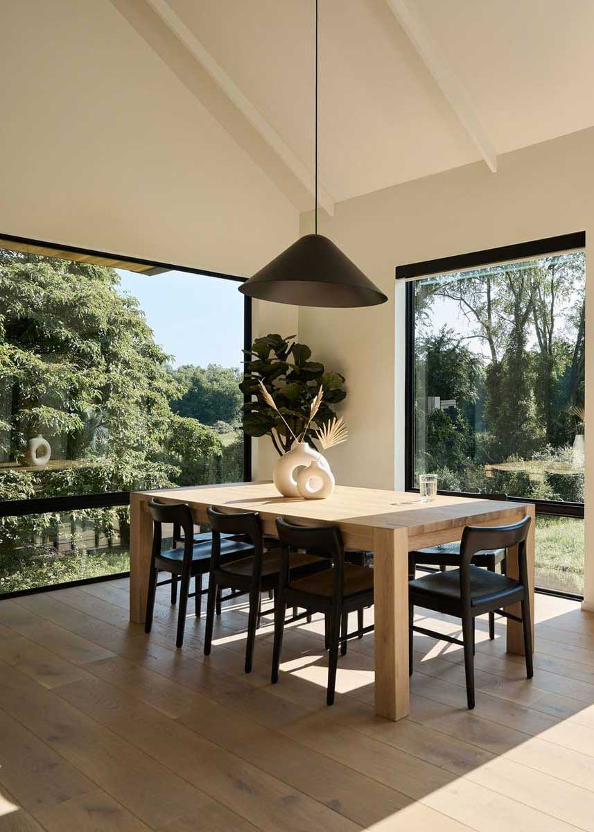 Two large Marvin Essential Direct Glaze windows anchor the corner of a dining table in a modern kitchen.