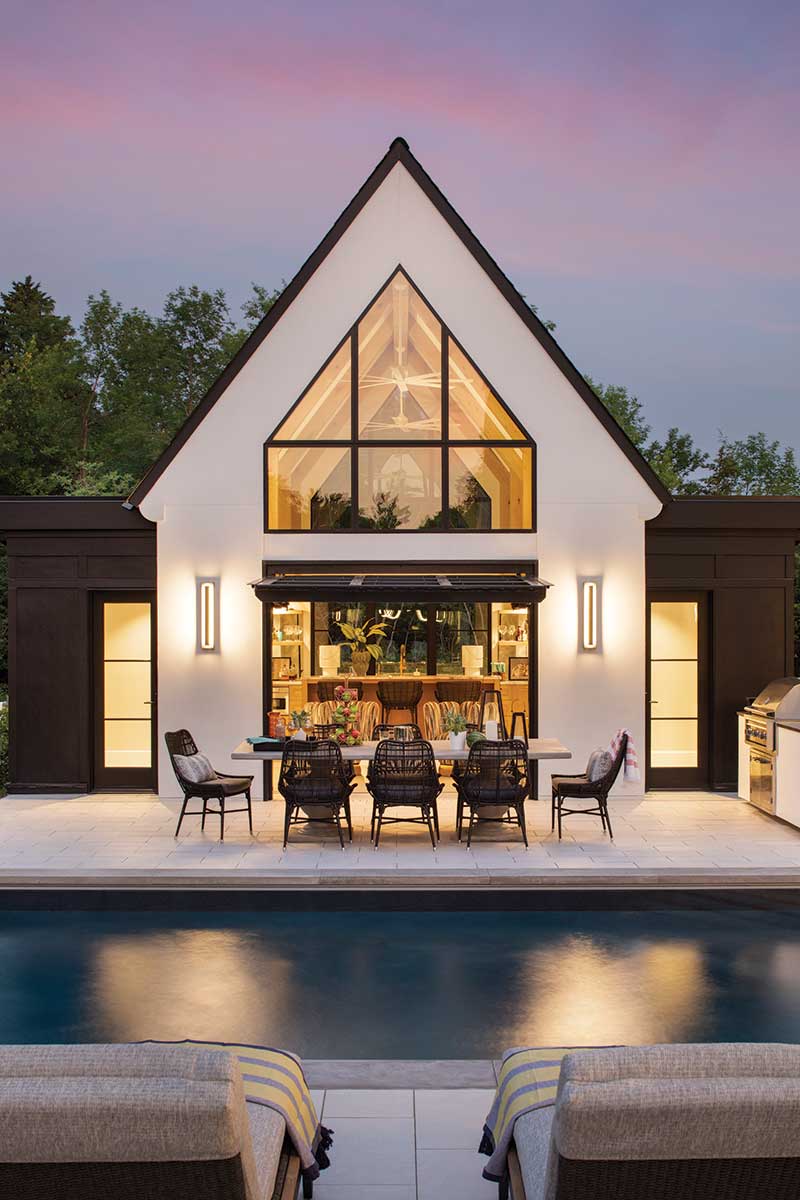 The pool deck and patio of a modern European home with a patio table and chairs and Marvin Modern windows and doors.