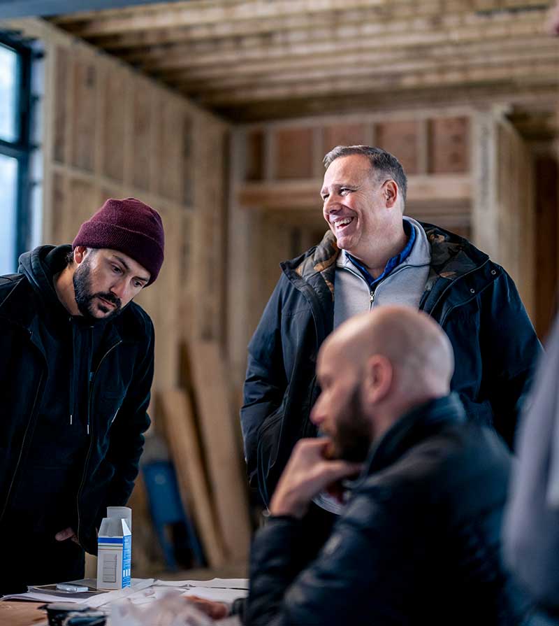 Three men talking in an under construction home.