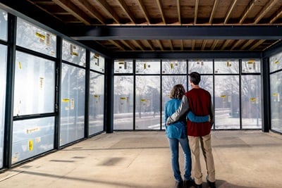 A man and woman standing in an under construction home, looking at a wall of Marvin Modern windows.