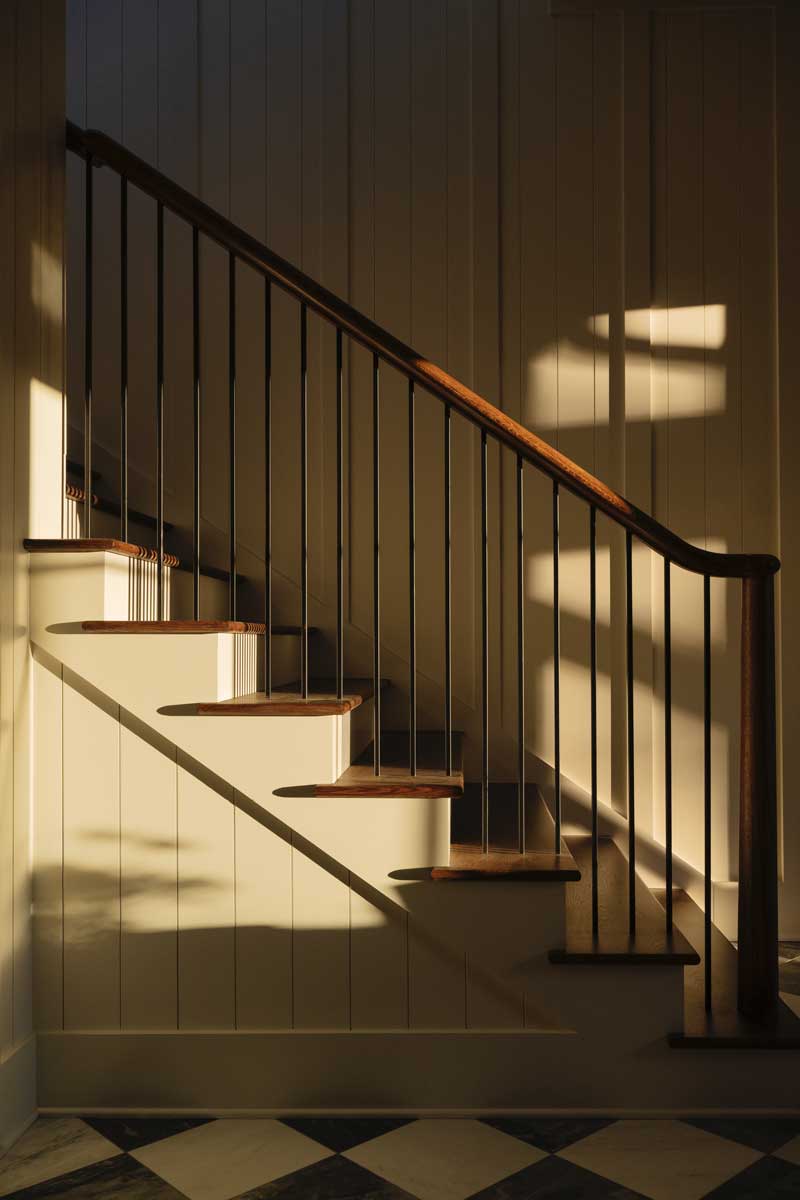 A staircase in with shadows from nearby Marvin windows inside the Southern Living Idea House 2023 in Leiper's Fork, TN.