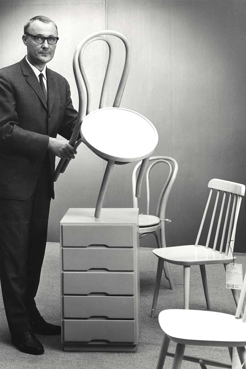 A historical photo of Ingvar Kamprad, founder of Ikea, holding a Scandinavian-style chair.