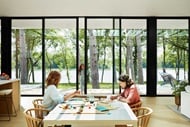 Family sitting at a dining room table looking out a Marvin Signature Modern Multi-Slide Door
