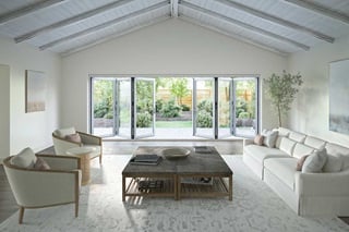 A Marvin Elevate Bi-Fold Door opening a living room with vaulted ceilings to a yard.