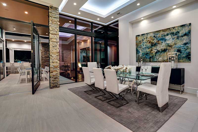 A Coastline Pivot door connects a contemporary dining room and an outdoor patio. 