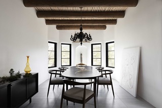 A dining space in an Adobe-style home in Santa Fe, New Mexico, featuring Marvin Ultimate windows and a black oval table.