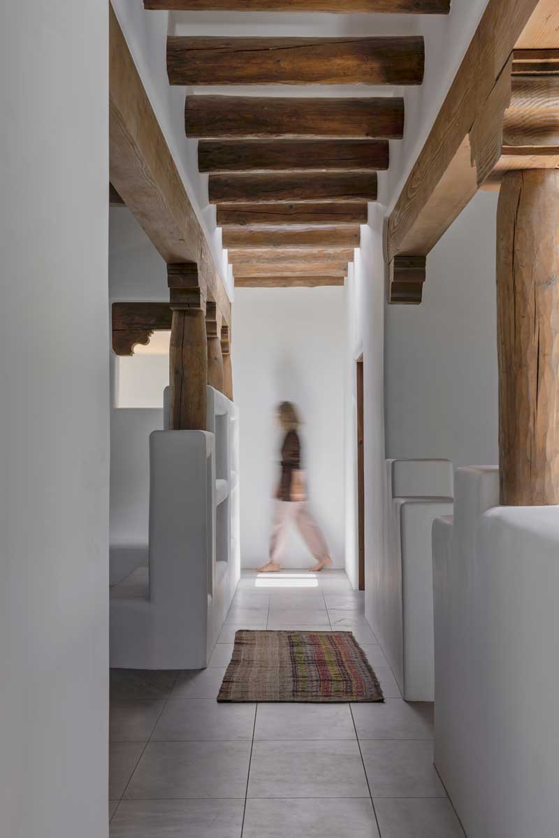 A woman walking through a hallway of an Adobe-style home in Santa Fe, New Mexico.