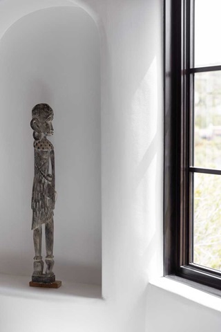 A statue in an Adobe-style home gazing out a black Marvin Ultimate Casement Picture window with simulated divided lites.