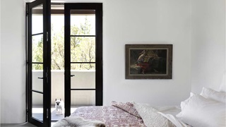 A bedroom in an Adobe-style home with a Marvin Ultimate Inswing French door with a French bulldog standing outside.