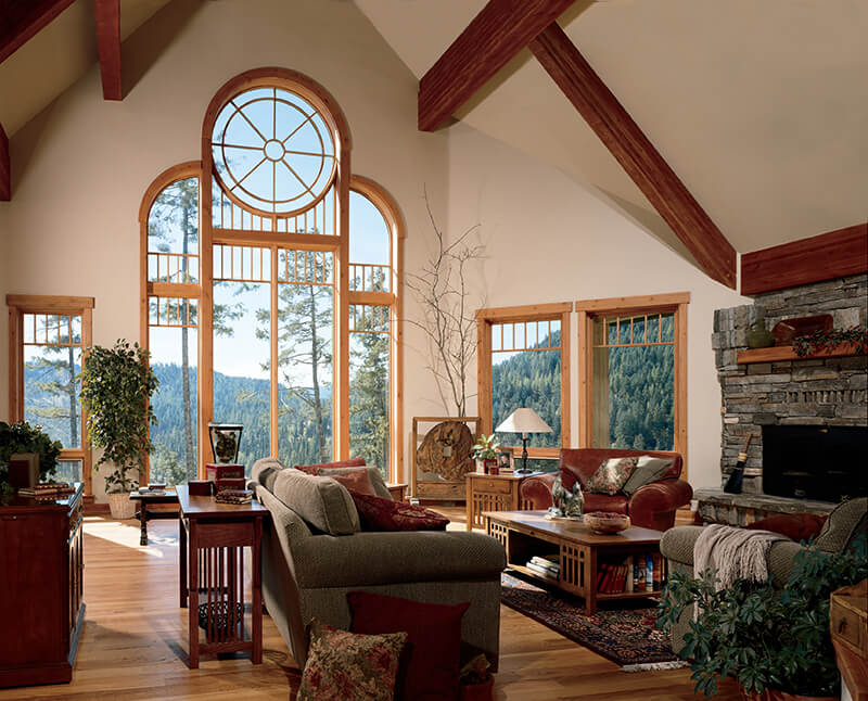 A living room with custom shaped windows with a nature view.