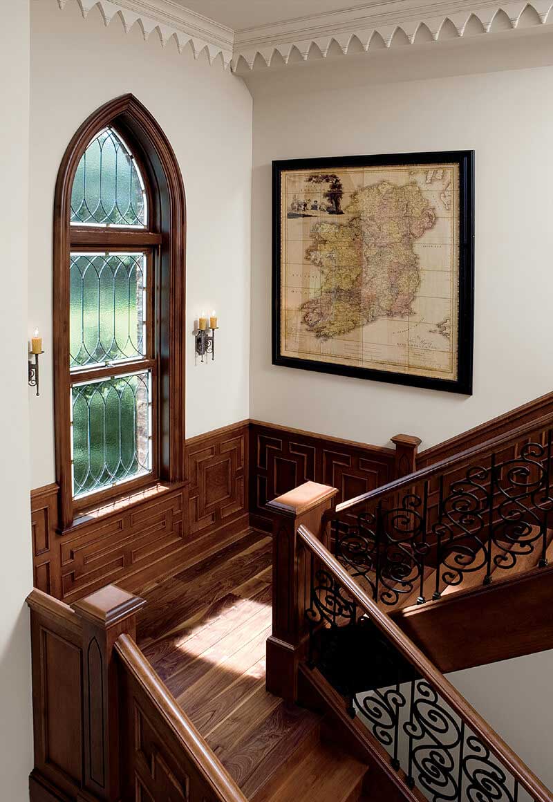An ornate staircase featuring a historic, decorative window.