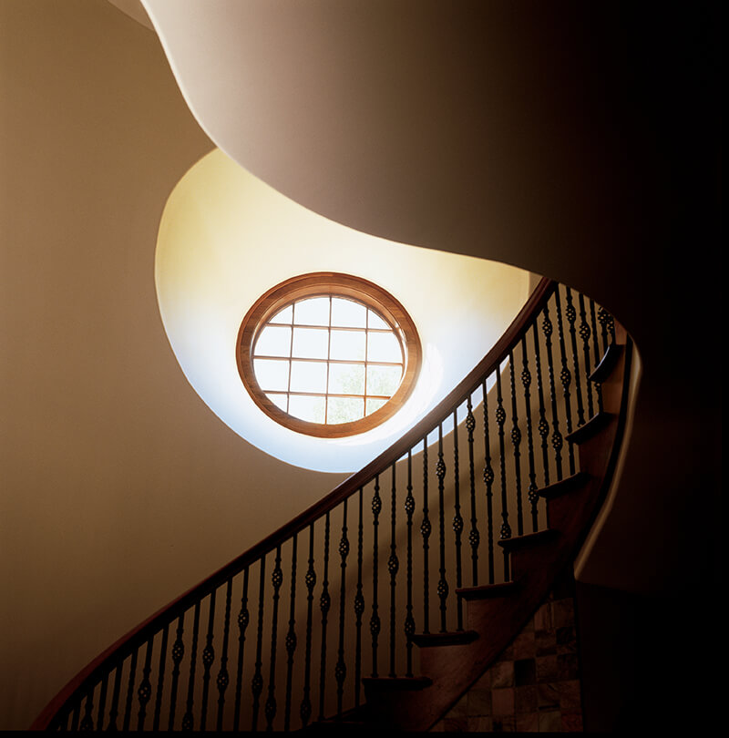 A curved staircase with a round Marvin window.