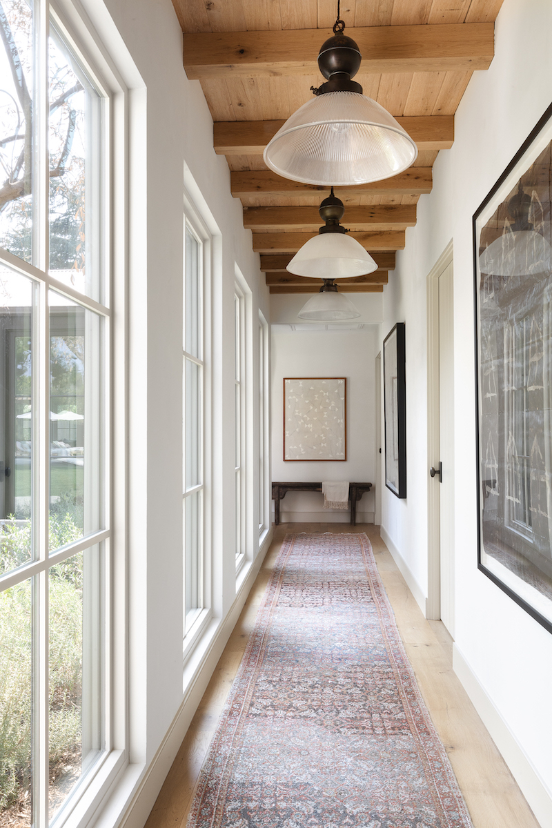 Hallway in Amber Lewis’s Belgian farmhouse-style home, featuring floor-to-ceiling Marvin Signature Ultimate windows.