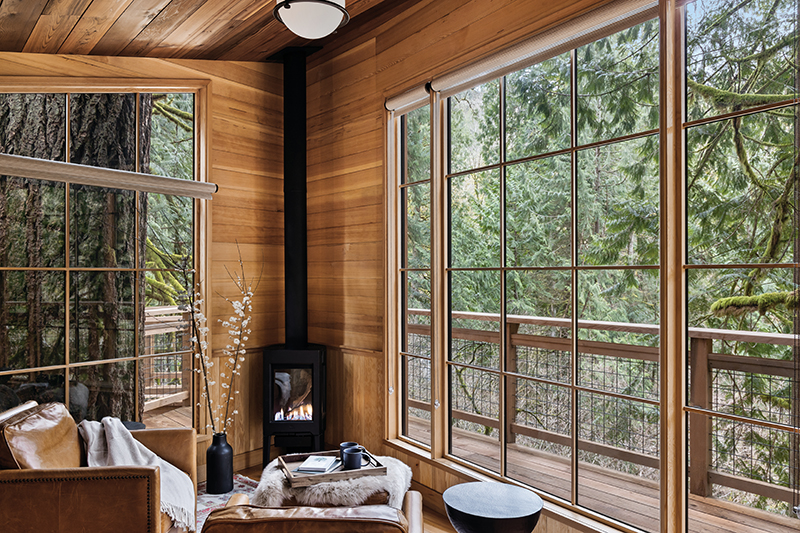 A sitting room with fireplace inside the Ananda Treehouse, an ADA accessible treehouse just outside of Seattle, featuring Marvin windows.