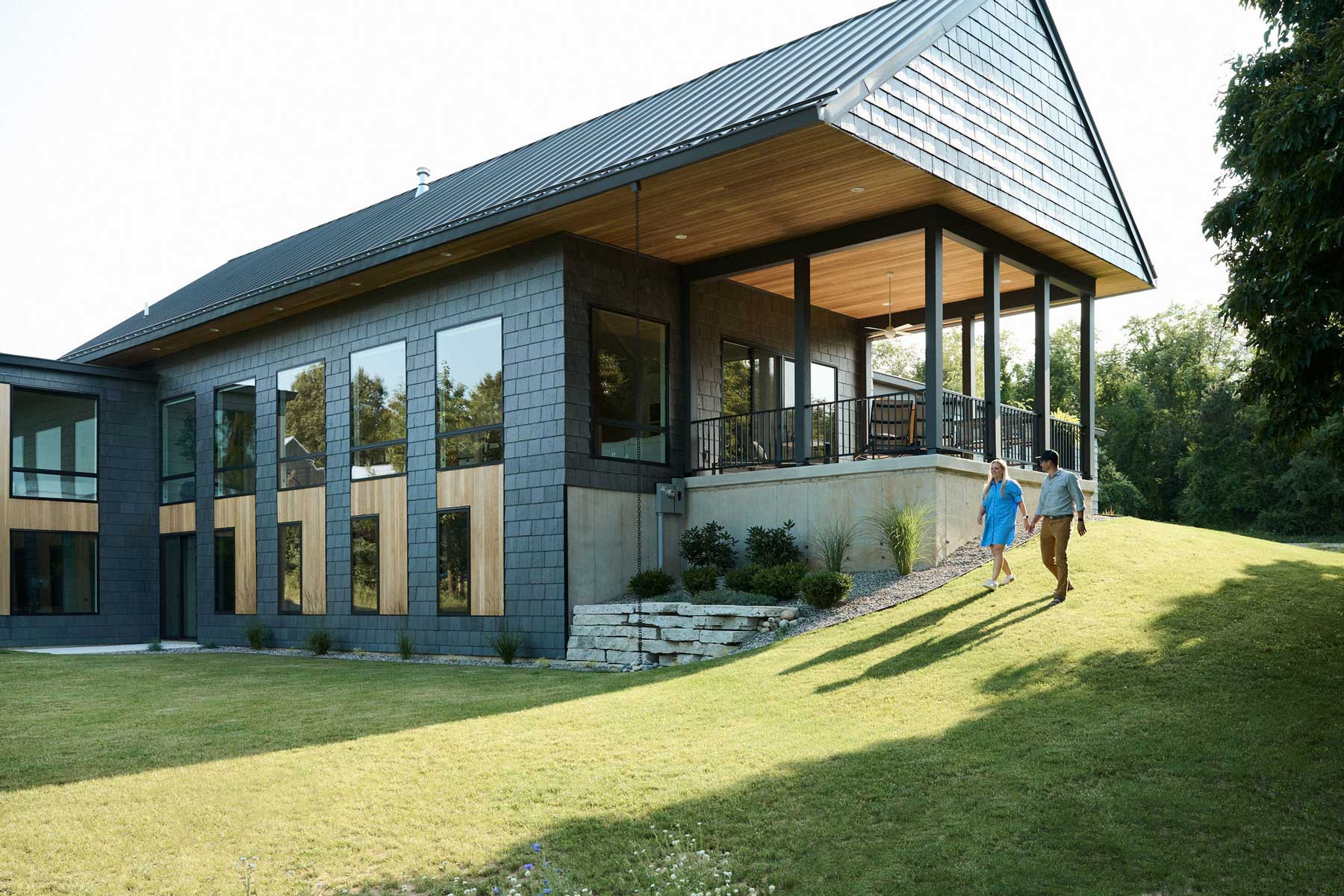 Two people walking around a modern home with Marvin Essential Direct Glaze windows and Essential Casement windows in Ada, Michigan.