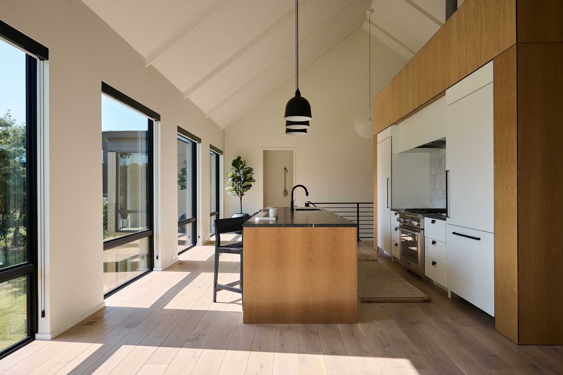 A modern kitchen centered around a white oak "cube" or a modern take on a scullery, with Marvin Essential Direct Glaze windows bringing in lots of natural light.