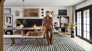 Bobby Berk and his dog in the dining room of the Bobby Berk Firm’s office, featuring a Marvin Ultimate Bi-Fold Door.