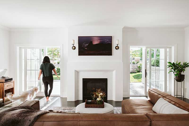 A woman in a modern-traditional living room featuring Marvin Essential sliding doors.
