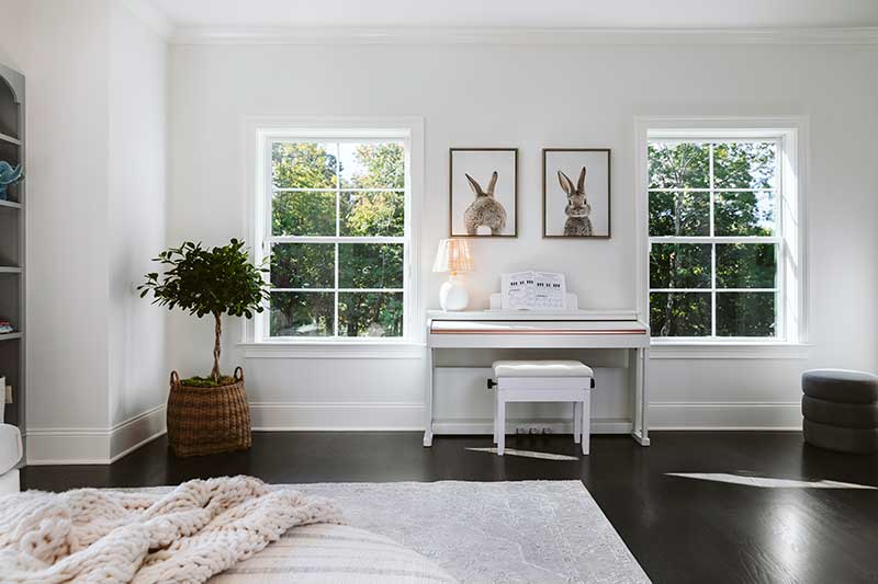 A bedroom featuring two Marvin Essential double hung windows and a piano.
