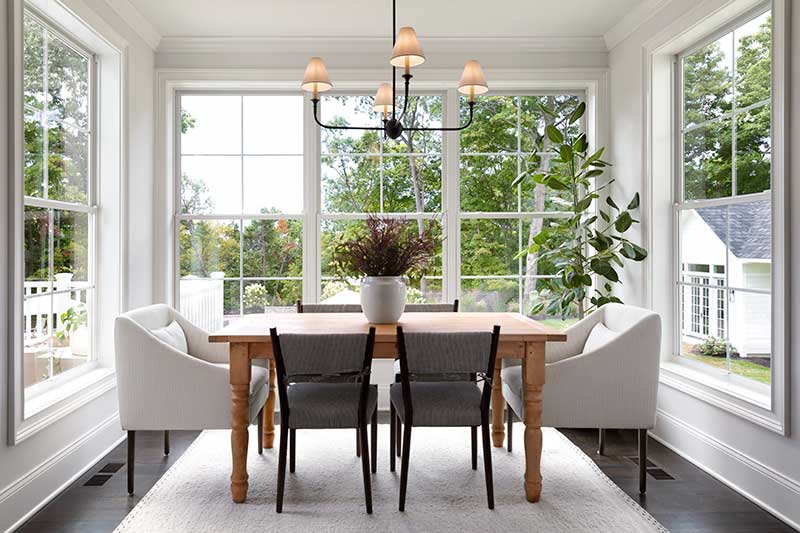 A modern-traditional dining room table surrounded by Marvin Essential windows.