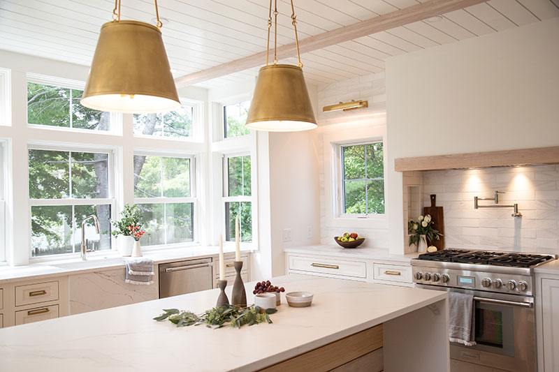 A modern white kitchen featuring Marvin Elevate double hung and casement windows and live edge waterfall island.