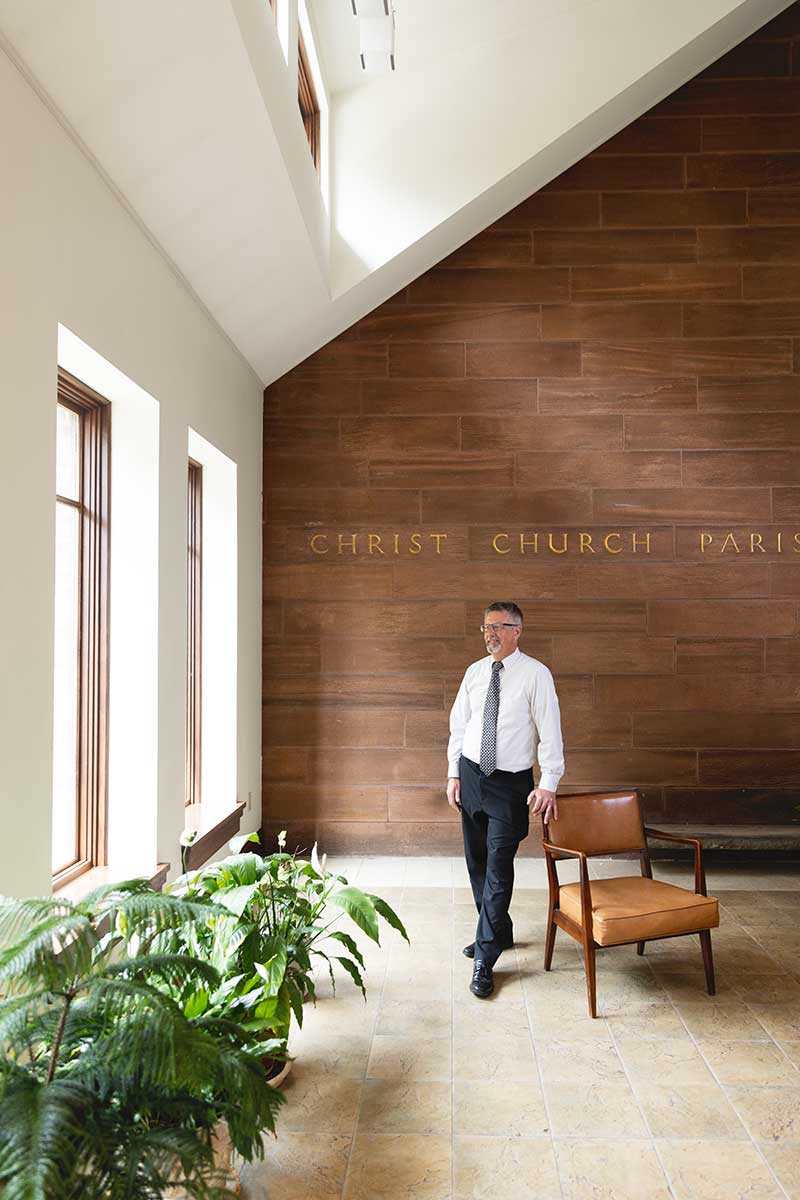Bob Conklin, vice principal and architect at Muhlenbreg Greene architects leaning on a chair inside Christ Episcopal Church in Reading, PA.