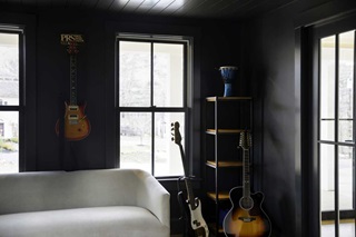An entertainment room with dark walls and ceiling and three guitars, featuring Marvin Elevate Double Hung windows with SDLs.