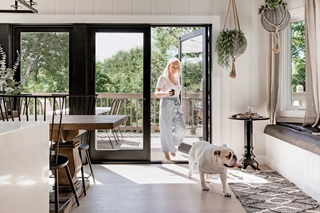 Katie Kurtz walking through a Marvin Elevate Outswing French door into her kitchen with her bulldog.
