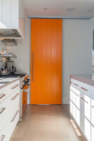 A closed orange Trustile barn door in a kitchen.