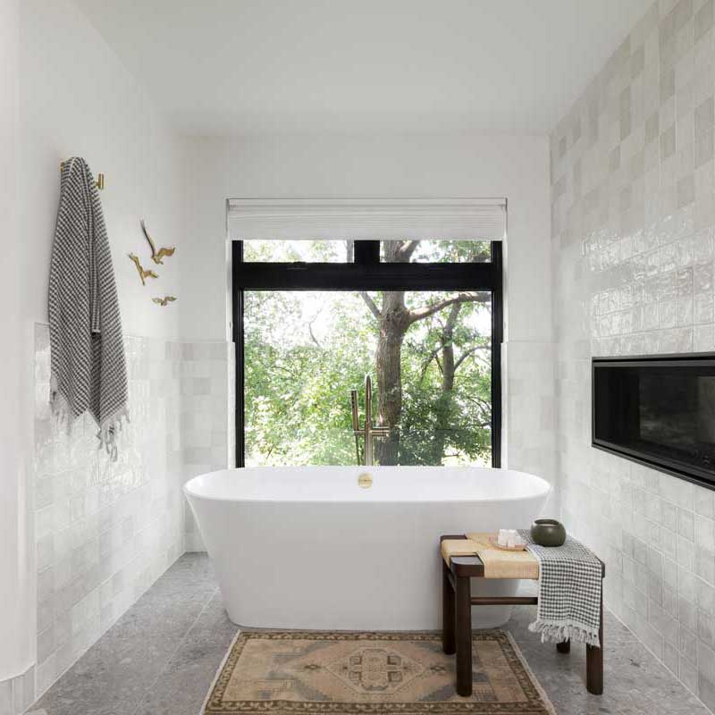 A modern bathroom with freestanding bathtub next to Marvin Essential Casement Picture and Essential Awning windows.