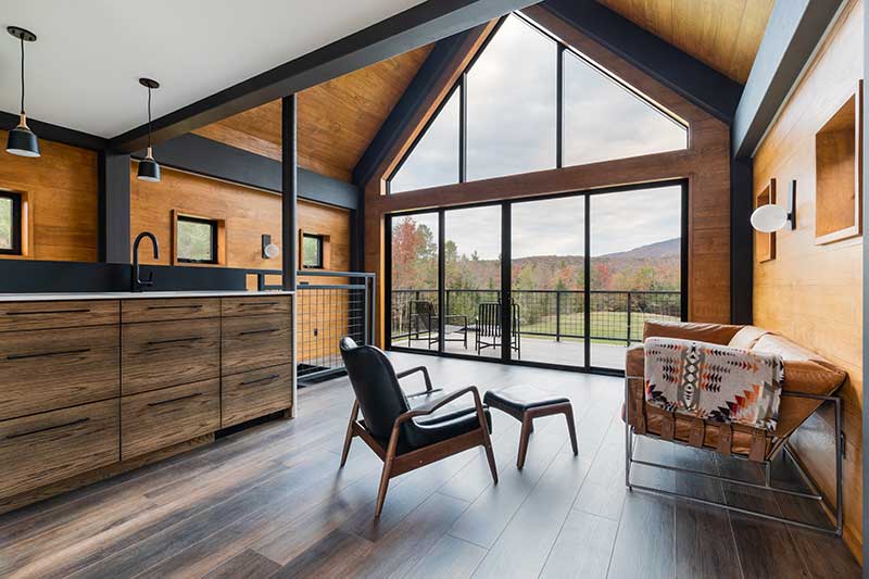 A view of Stratton Mountain in Vermont through the Marvin windows and sliding patio door of a modern barn-style guest house.