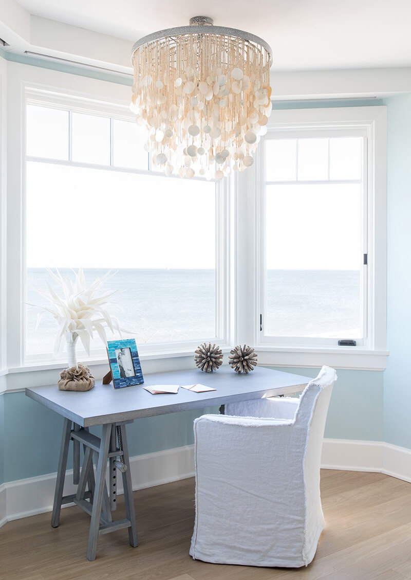 A desk with a view of the ocean through Marvin windows.