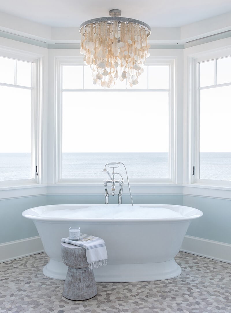 A large bathtub with a view of the ocean through Marvin windows.