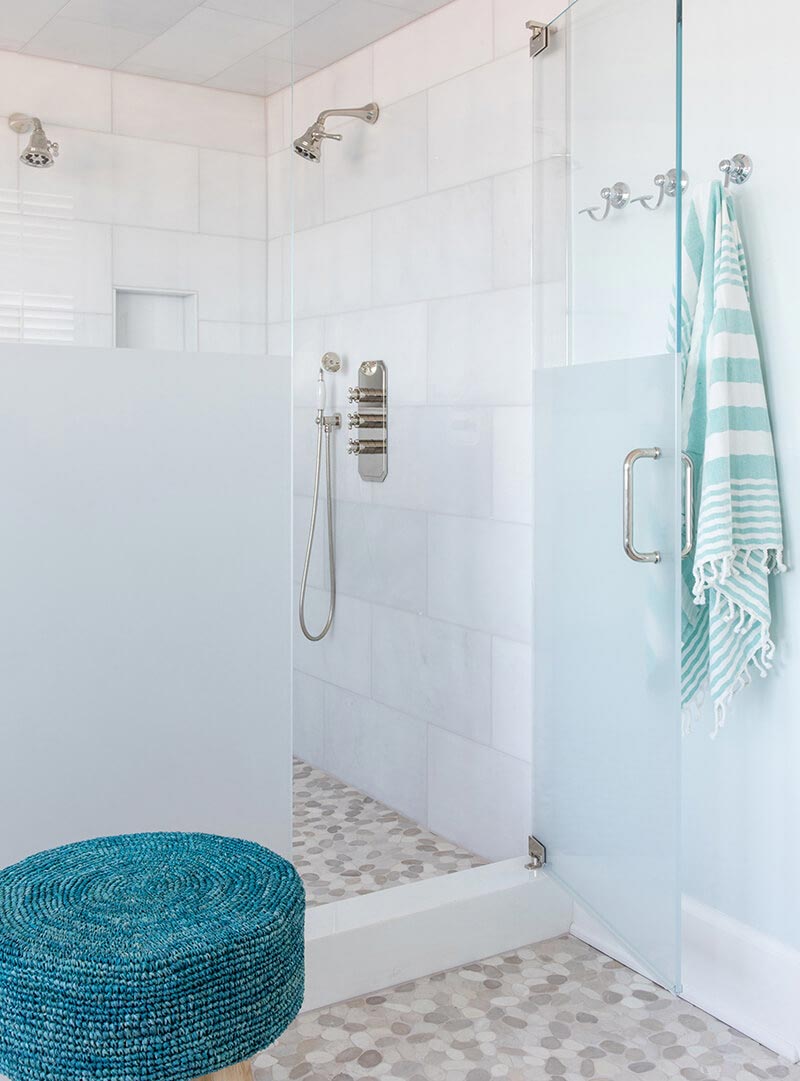 A white-tiled walk-in shower with silver fixtures.