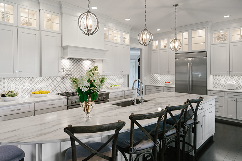 A bright white contemporary kitchen with white cabinets, countertops and backsplash.