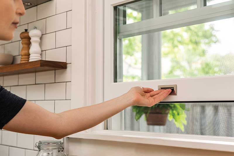 Woman opens Marvin Ultimate Single Hung window in kitchen.
