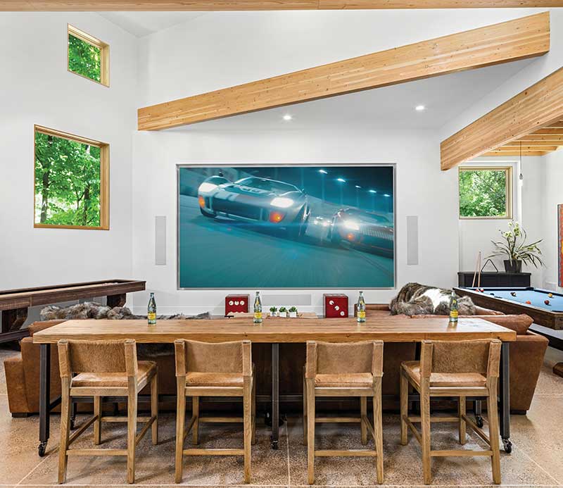 An entertainment center with a big-screen TV and pool table includes Marvin Ultimate Picture windows strategically installed to make the best use of natural light.