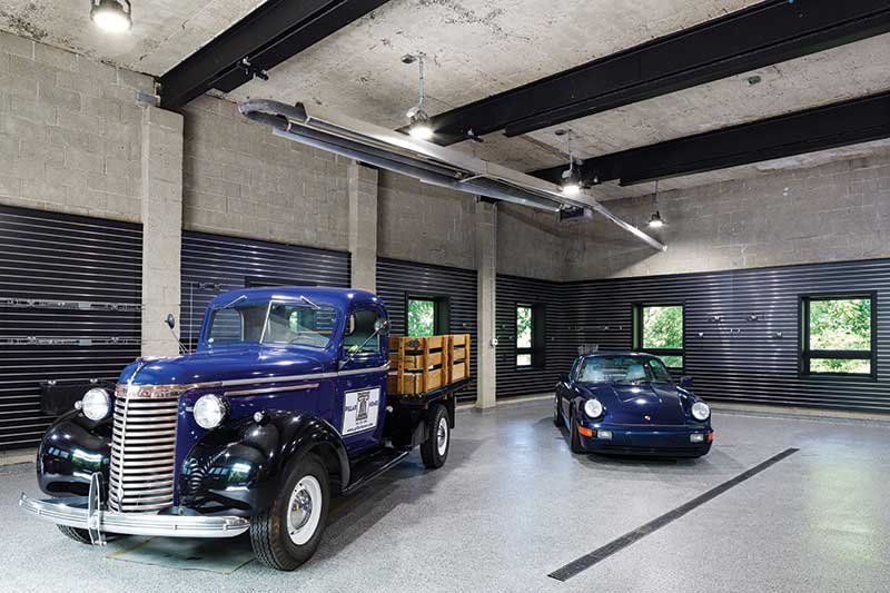 Two collector cars on display in a modern-industrial home’s garage, featuring Marvin Ultimate Awning windows. 