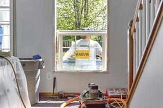 man installing a replacement double hung window in rough opening.