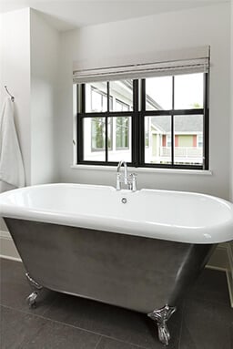 Traditional claw foot tub in front of a Marvin Window