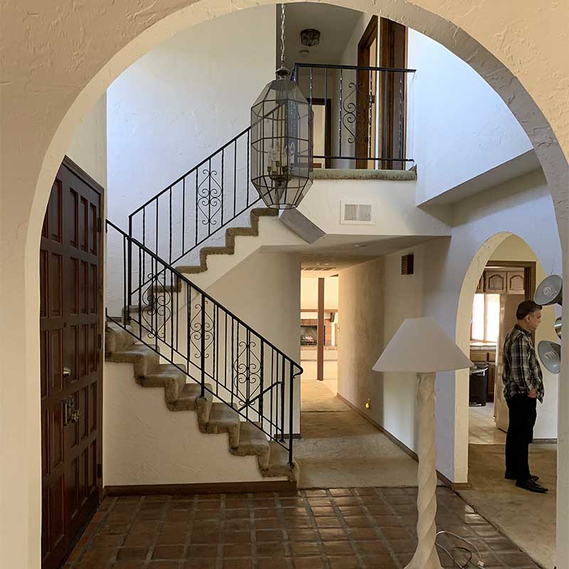 A before image of the staircase in the Bobby Berk Firm’s office space, which was previously a dated 70s Spanish Mediterranean home. 