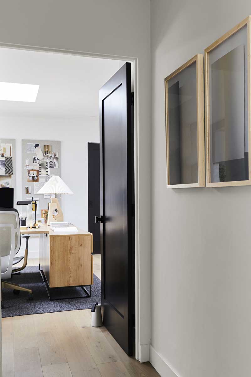 A look into the work space of the Bobby Berk Firm’s office through a black interior door.