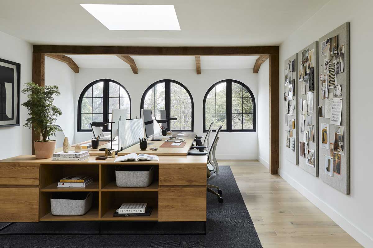 The office of the Bobby Berk Firm, with Marvin Ultimate Round Top windows, mood boards on the wall and three desks with Mac computers in the middle of the room.
