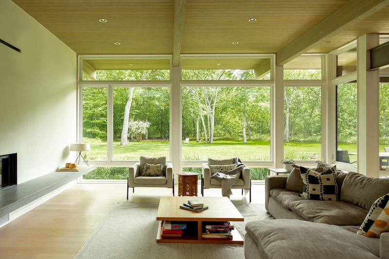 A living room with Marvin Ultimate casement and picture windows that frame the landscape on the property.