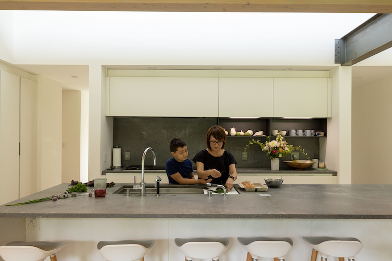 A mother and son cooking together in a large modern kitchen.