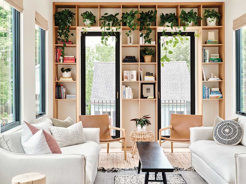 The second floor living room of a modern railroad-style home in New Orleans, filled with plants, and Marvin windows and doors.