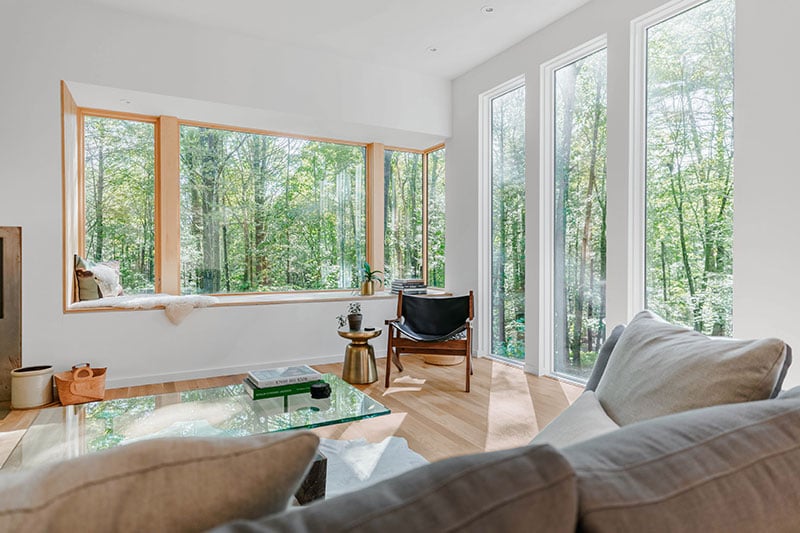 A contemporary living room featuring a window nook beneath a Marvin Ultimate Corner window.