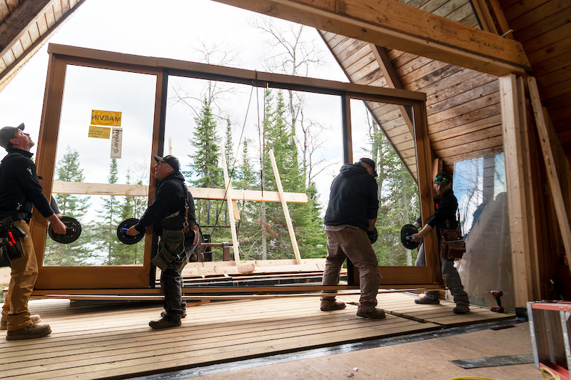 Four men installing a Marvin Signature Ultimate Sliding French Door at The Minne Stuga, an A-frame cabin in Grand Marais, MN.