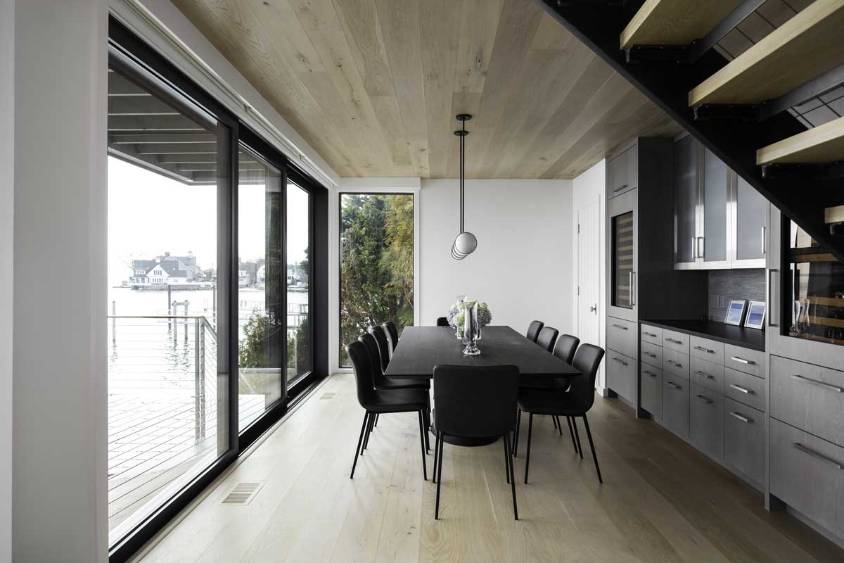 The dining room of a modern home in Norwalk, CT, with black table and chairs and a Marvin Modern Multi-Slide door.